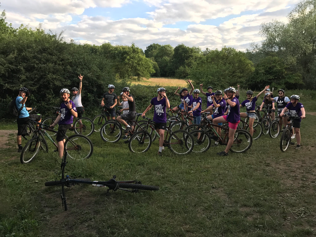 a large group of children riding mountain bikes in Epping Forest during summertime